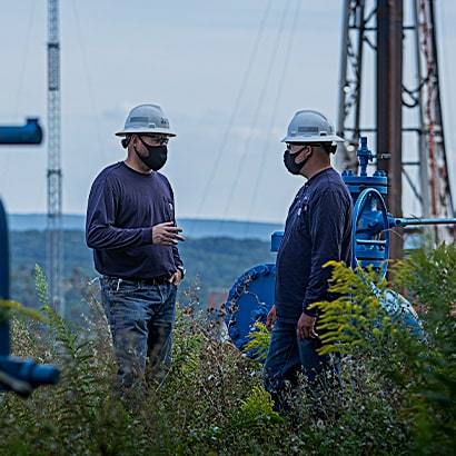 two workers wearing masks at rig site