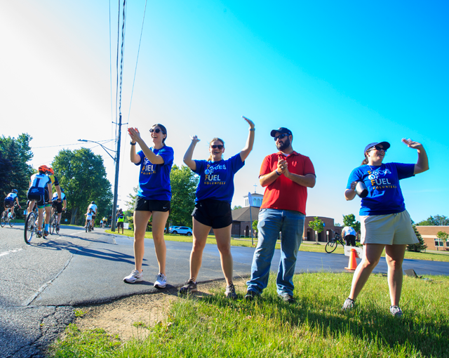 group of employees raising arms in the air cheering for a bike race