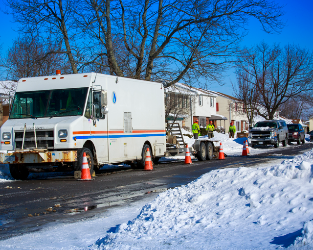 Utility truck with a crew outside on a snowy winter street